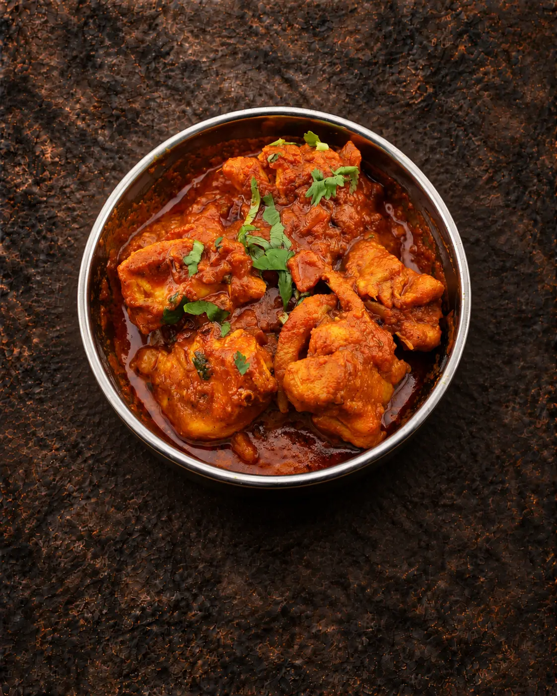 Fiery red Vindaloo curry in a steel bowl